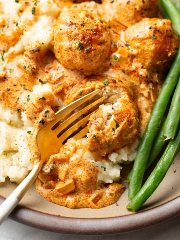 a plate with paprika chicken meatballs, mashed potatoes, and green beans