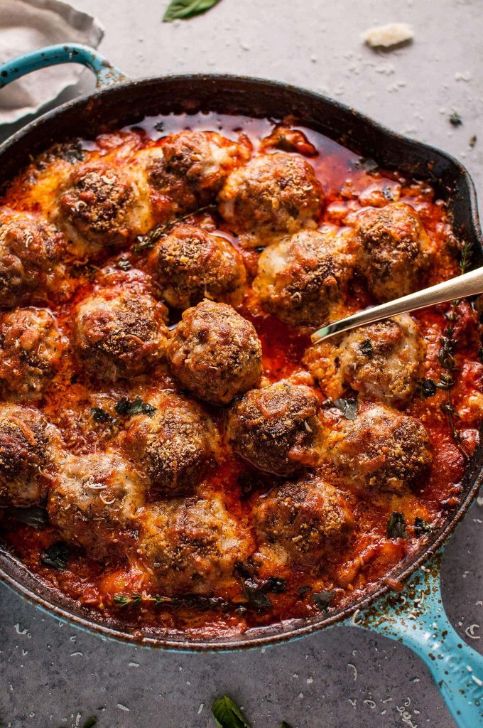 close-up of cheesy skillet meatballs with serving spoon