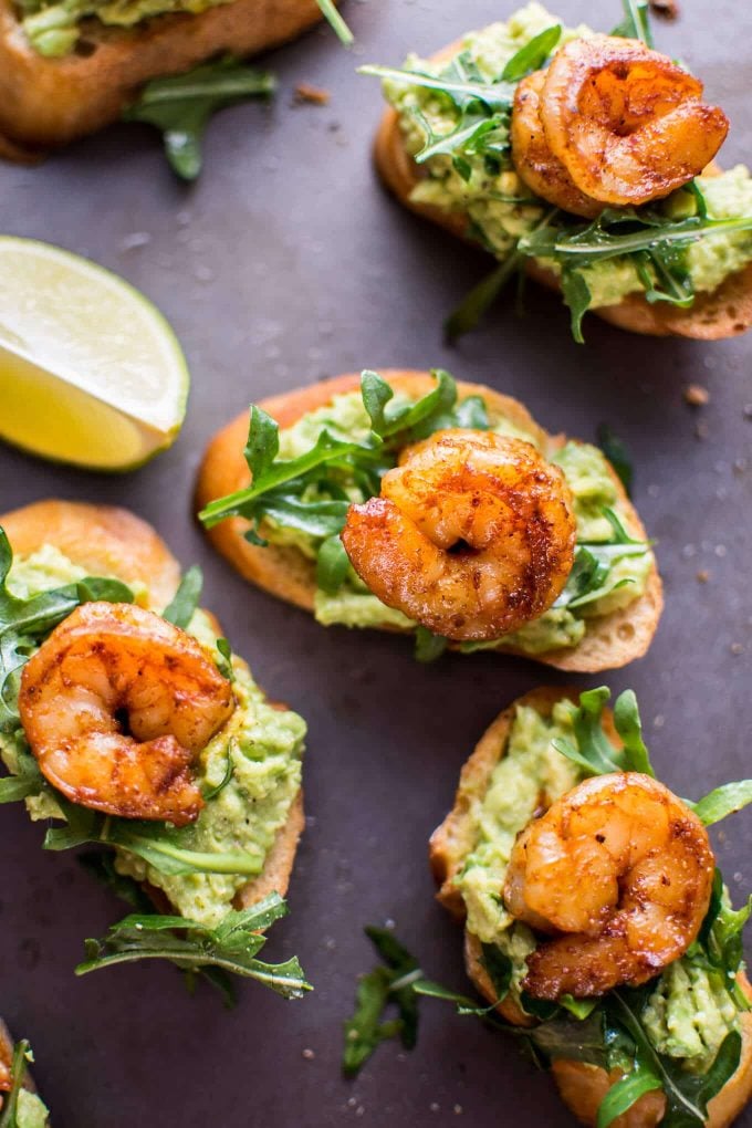 garlic shrimp and avocado crostini beside lemon wedge