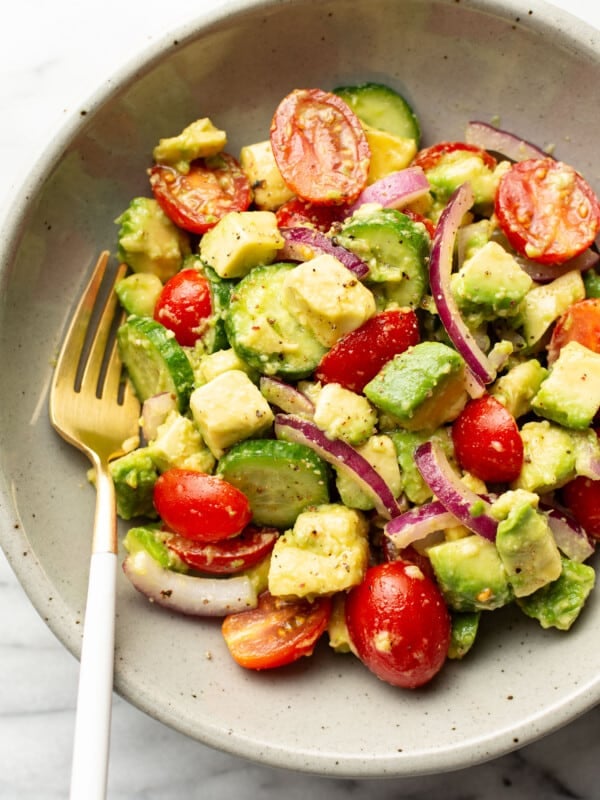 a bowl of cucumber tomato avocado salad with a fork