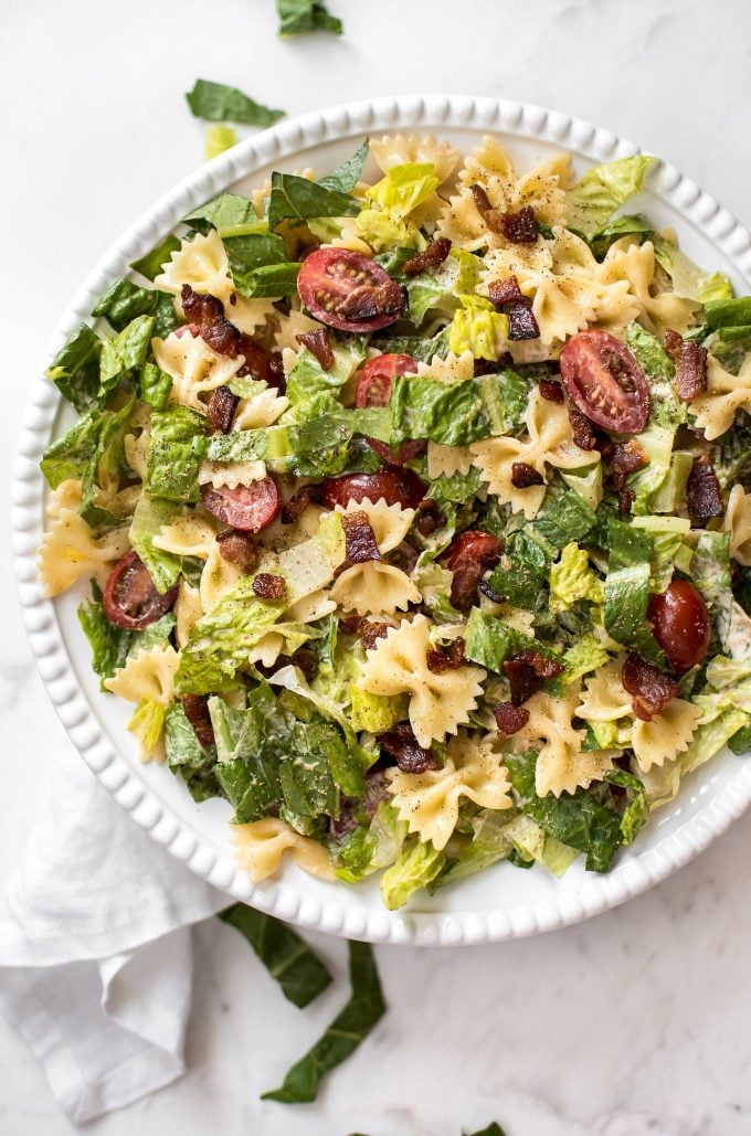 summer pasta salad with bacon, lettuce, tomatoes on a white plate
