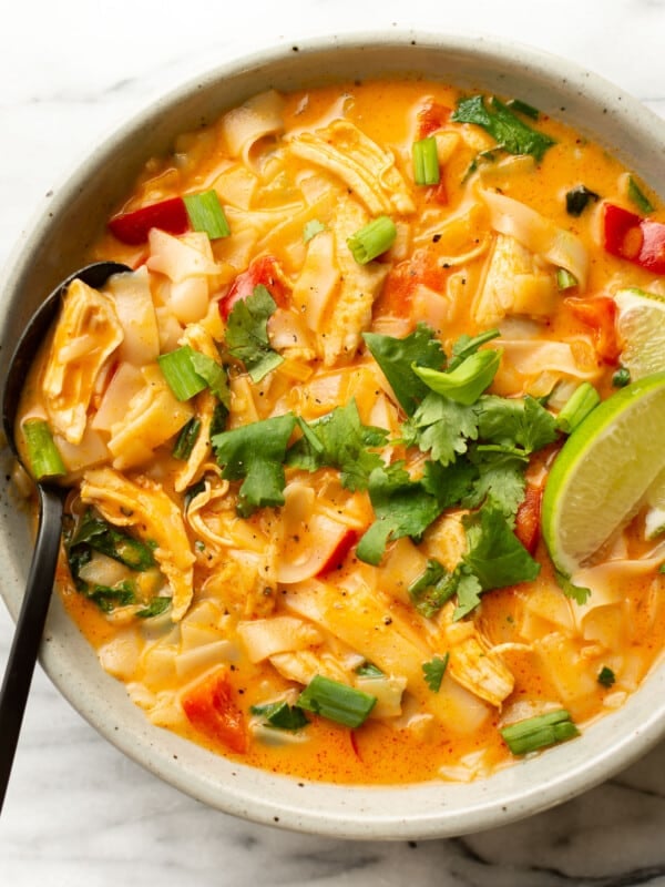 a bowl of thai turkey soup with a lime wedge and a spoon