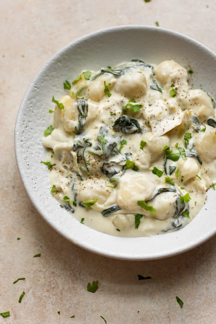 white bowl with spinach and artichoke creamy gnocchi