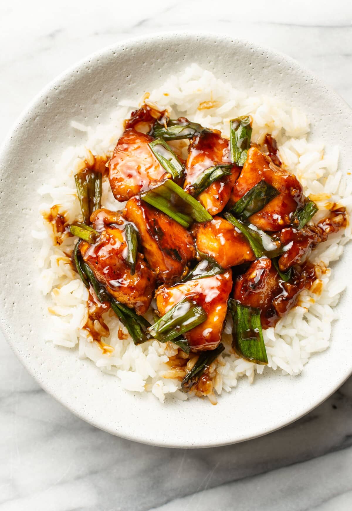 a bowl with mongolian chicken over rice
