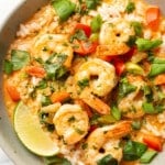 a bowl of thai shrimp curry over rice with a lime wedge