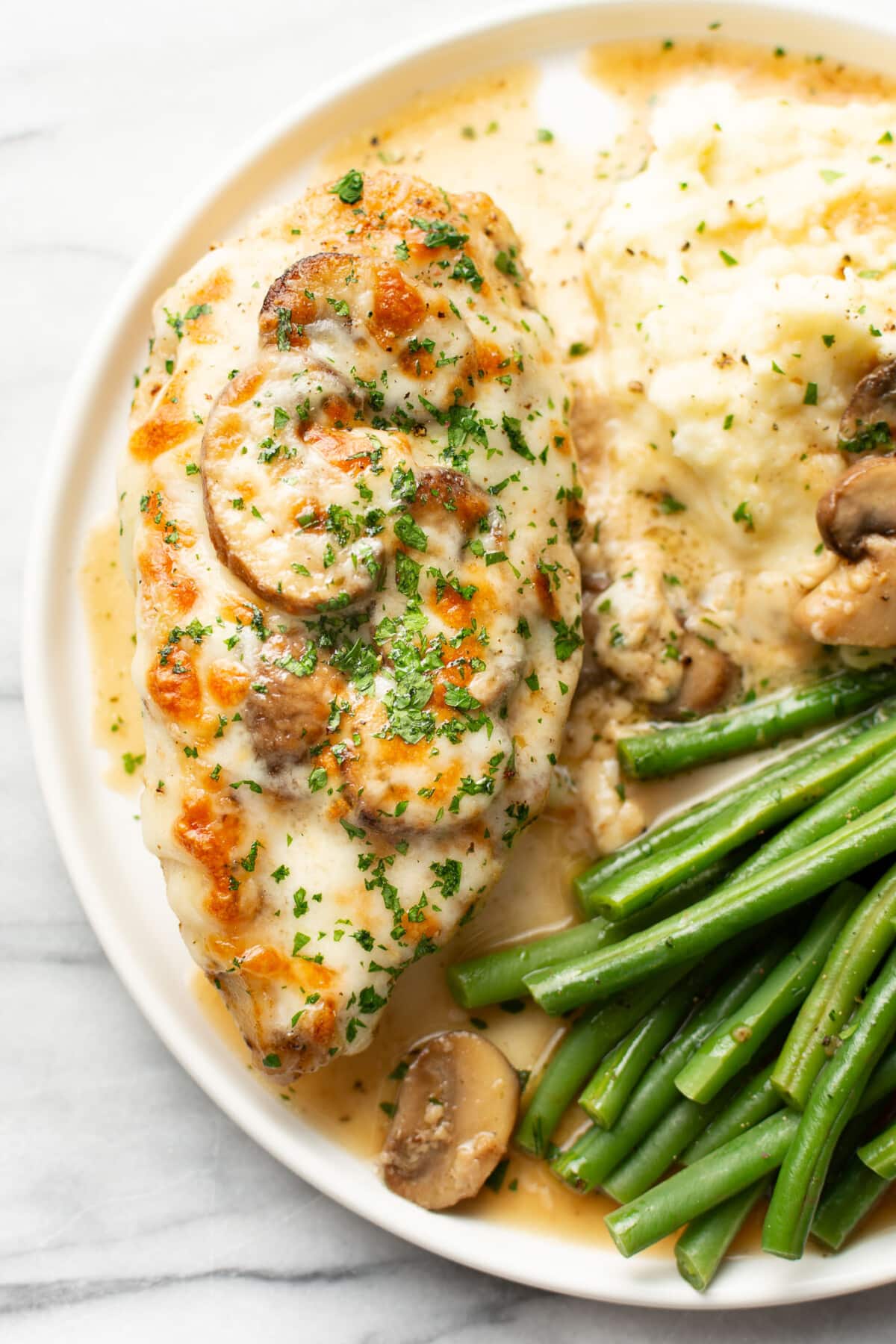 a plate with mozzarella mushroom white wine chicken, mashed potatoes, and green beans
