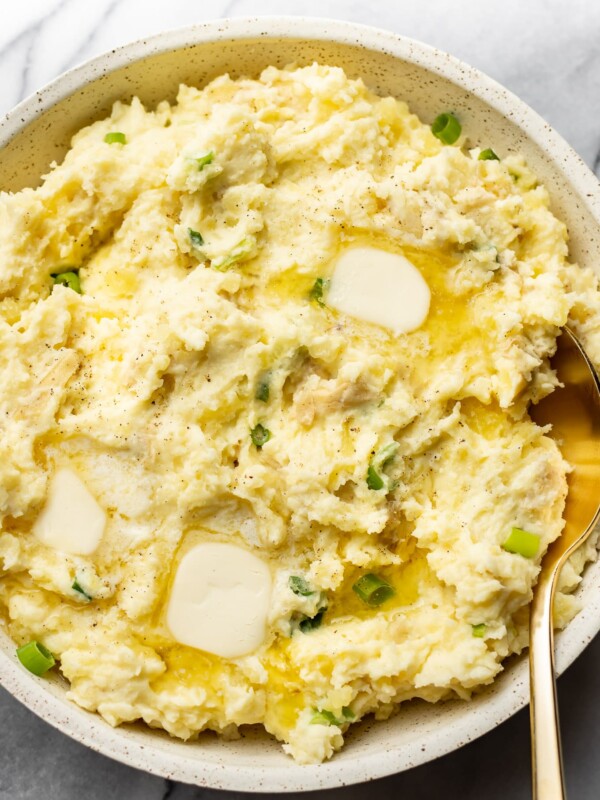close-up of cream cheese mashed potatoes in a serving bowl with a gold spoon