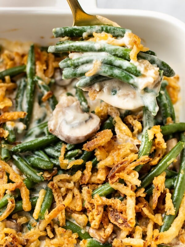 close-up of green bean casserole (from scratch) in a white baking dish with a spoonful being taken out