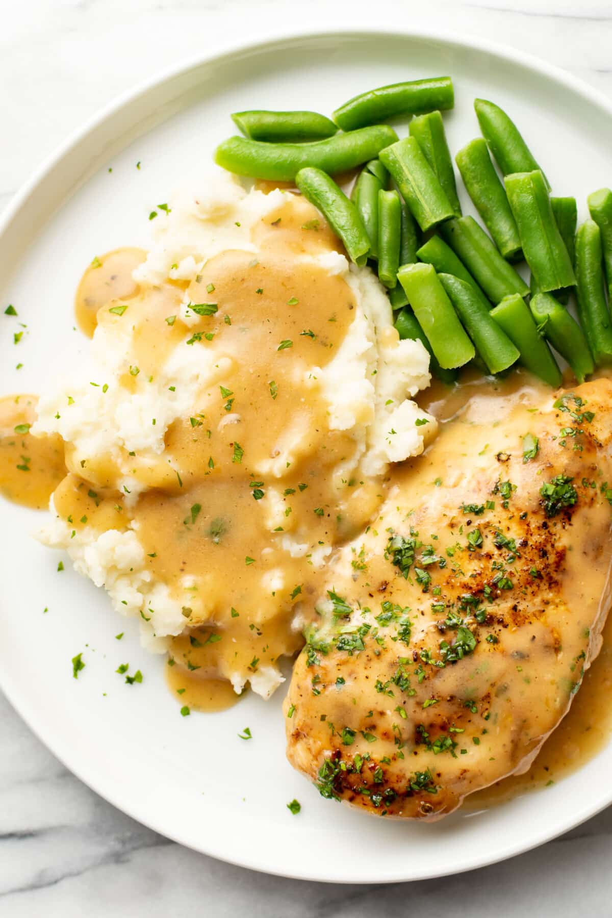 a plate with ranch chicken and gravy, green beans, and mashed potatoes