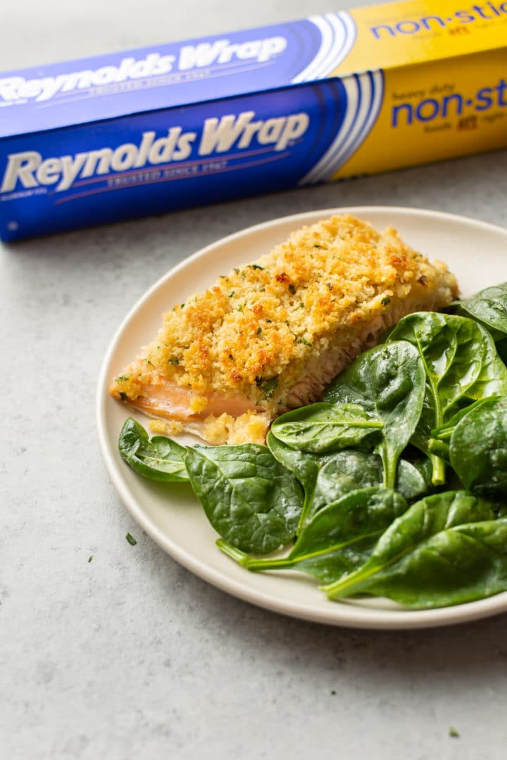 maple dijon baked salmon on a plate with spinach (Reynolds Wrap foil in the background)