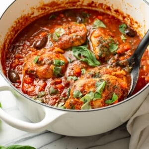 a dutch oven with chicken cacciatore and a serving spoon