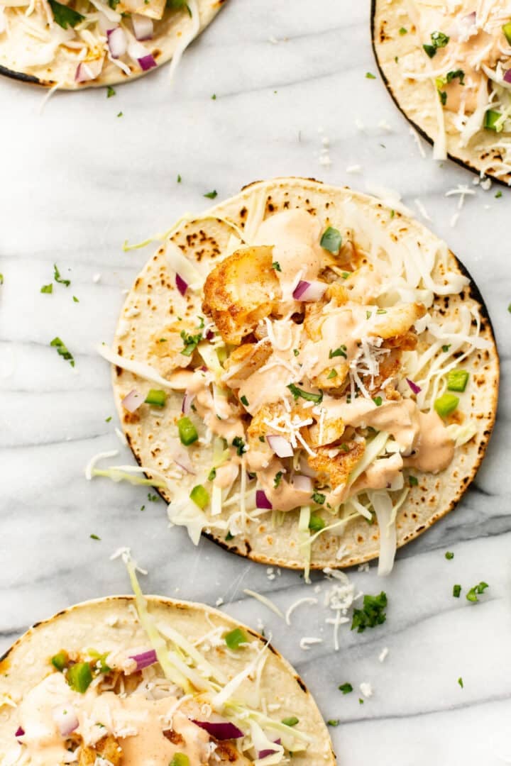 several fish tacos on a marble surface