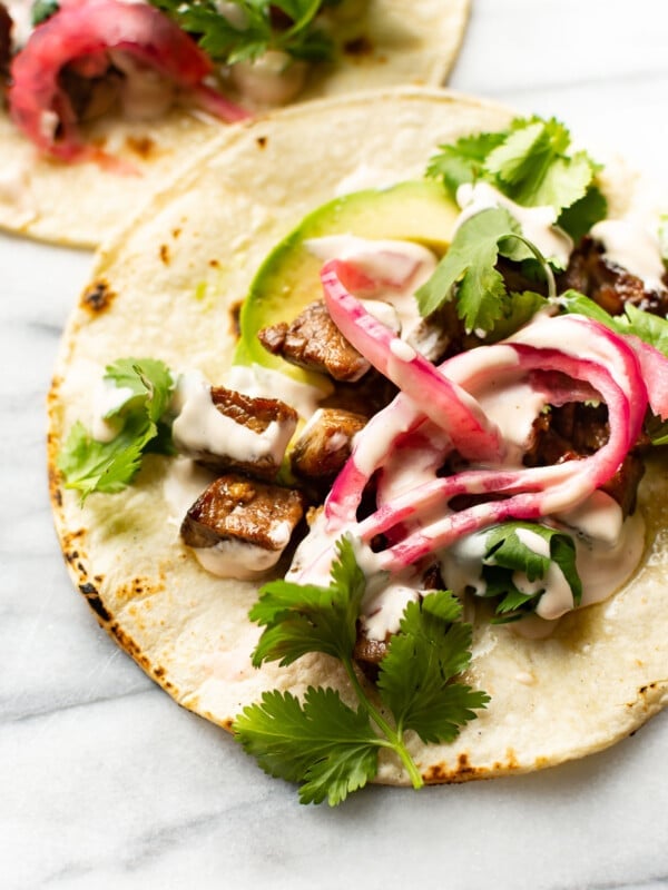 two steak tacos on a marble surface