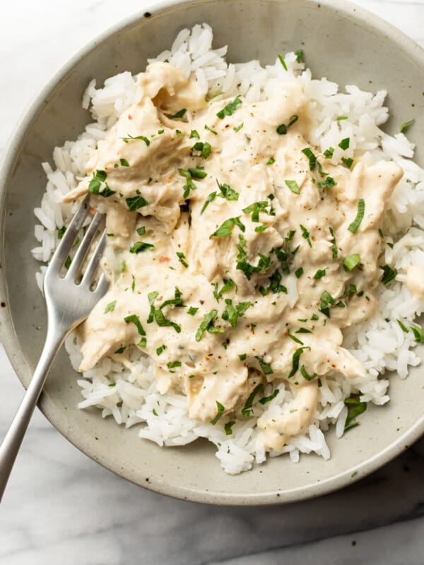 a bowl of crockpot italian chicken over rice with a fork