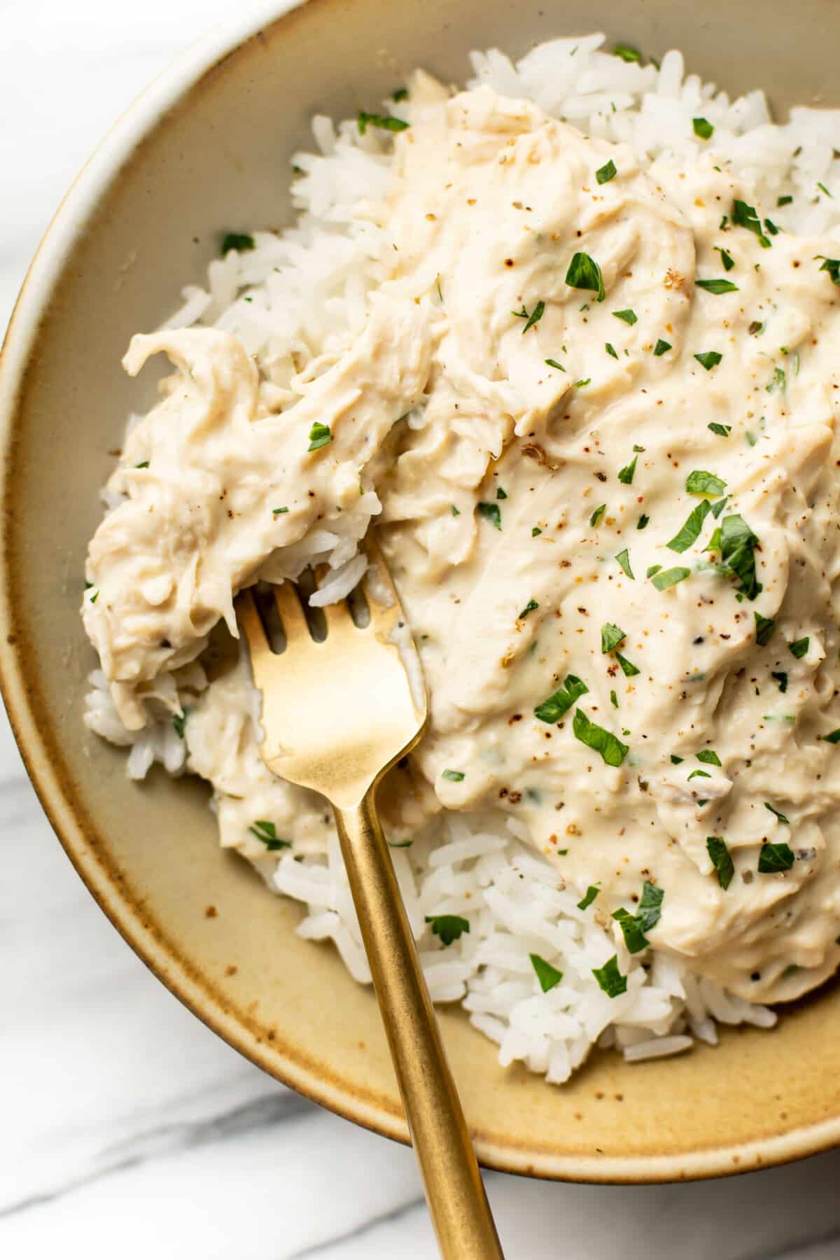 a bowl of crockpot ranch chicken with rice and a fork