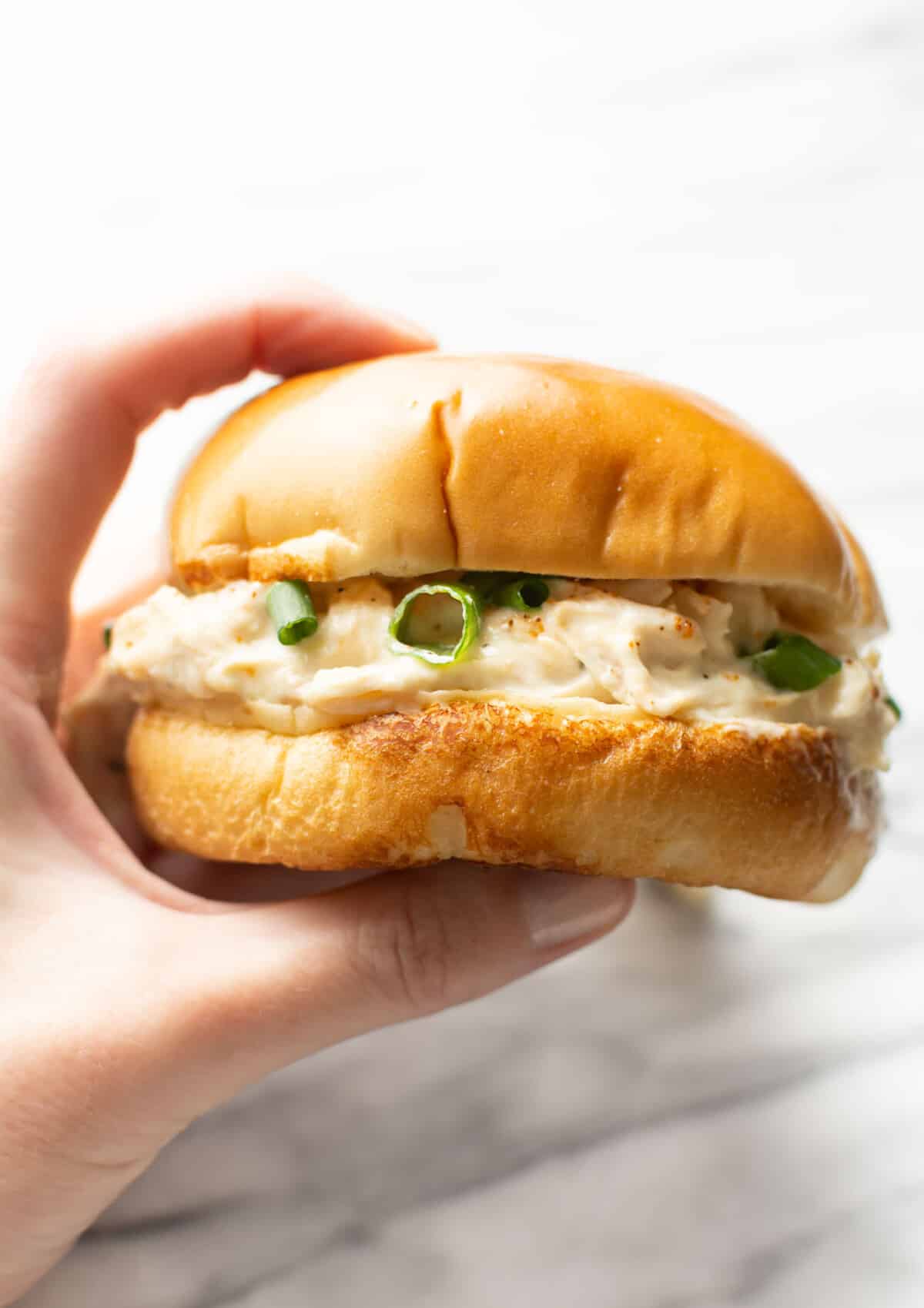a female hand holding a ranch chicken sandwich on a brioche bun