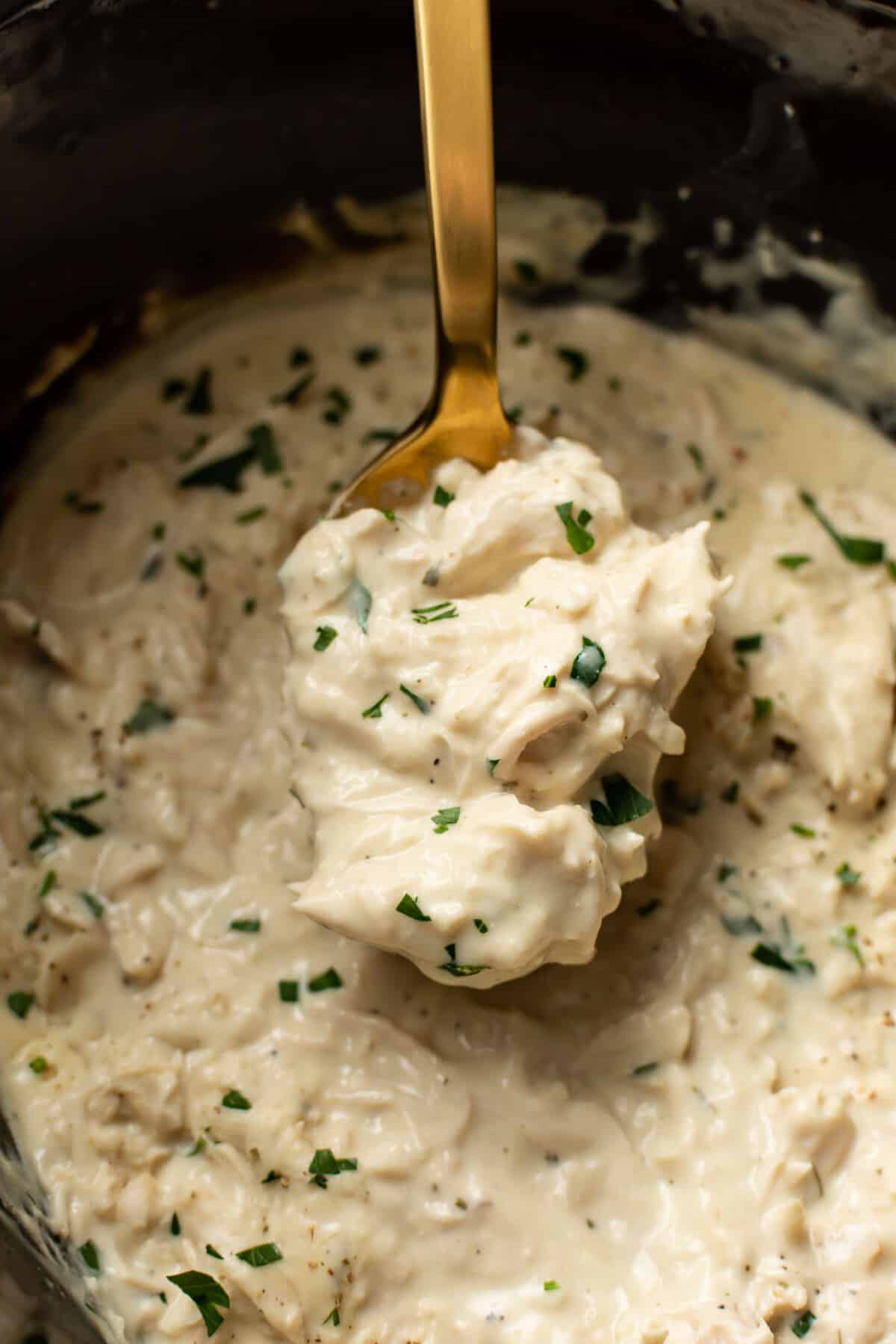 a crockpot with ranch chicken and a serving spoon