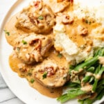 a plate with marry me pork tenderloin, mashed potatoes, and green beans
