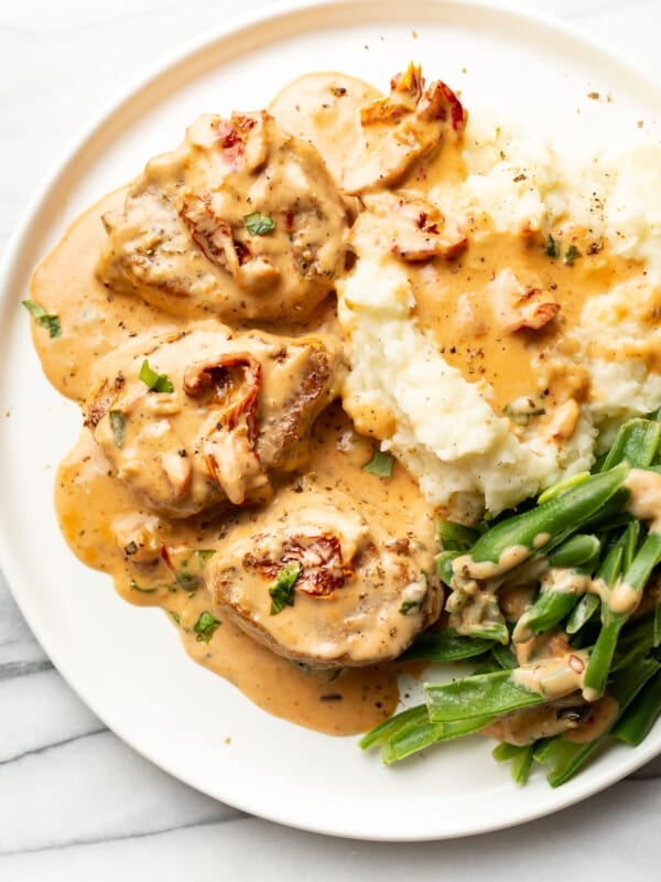 a plate with marry me pork tenderloin, mashed potatoes, and green beans