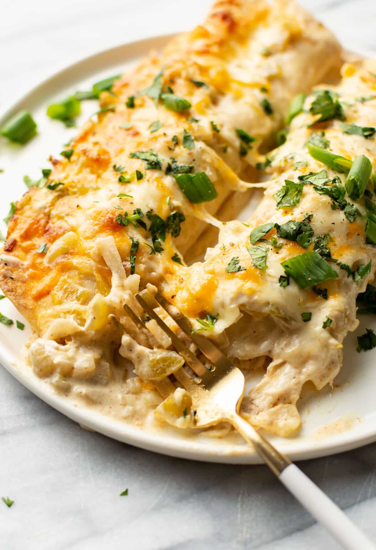 a plate with chicken enchiladas and a fork