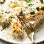 a plate with halibut, a creamy sauce, green beans, mashed potatoes, and a fork