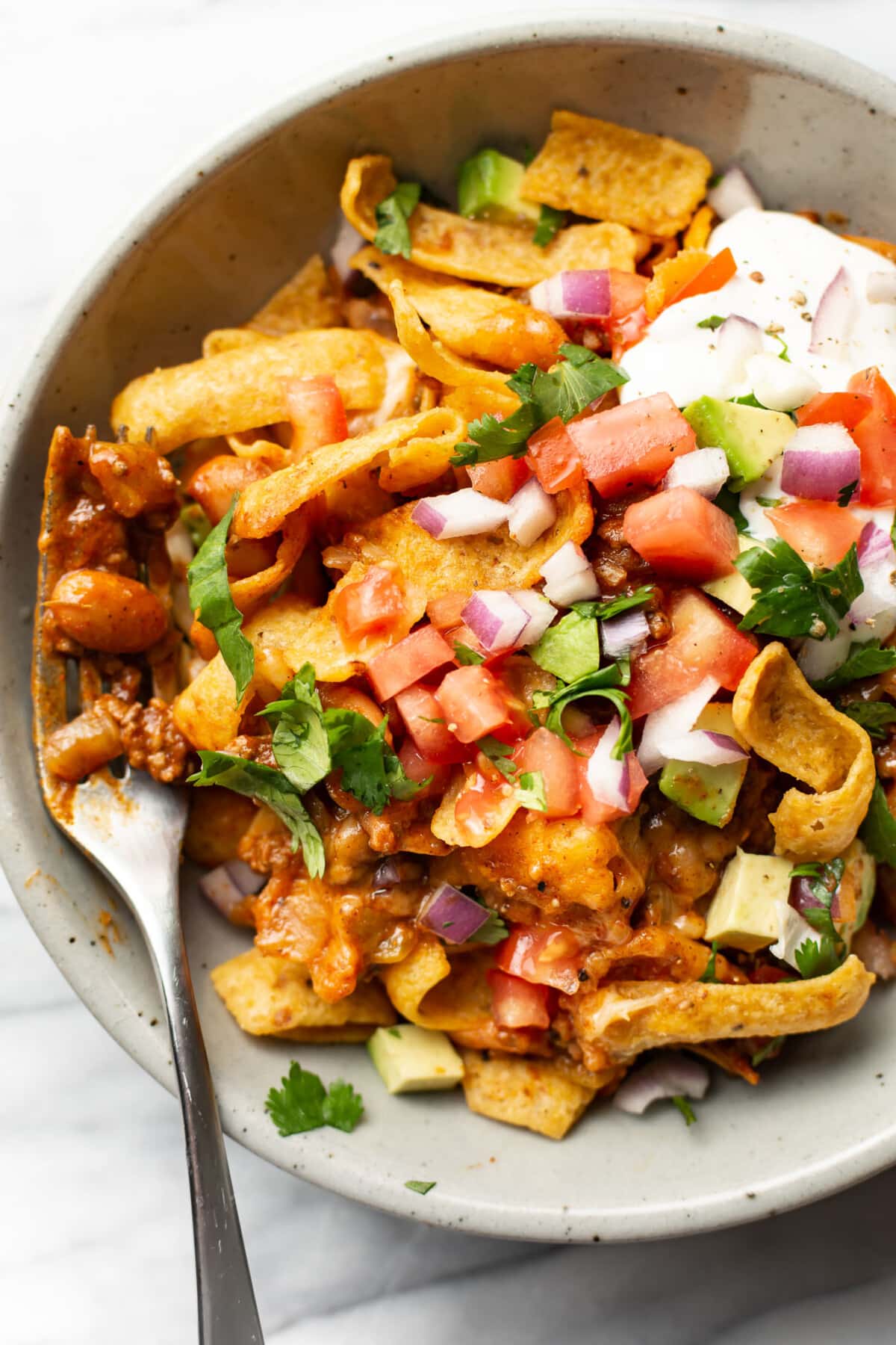 a bowl of frito pie with a fork