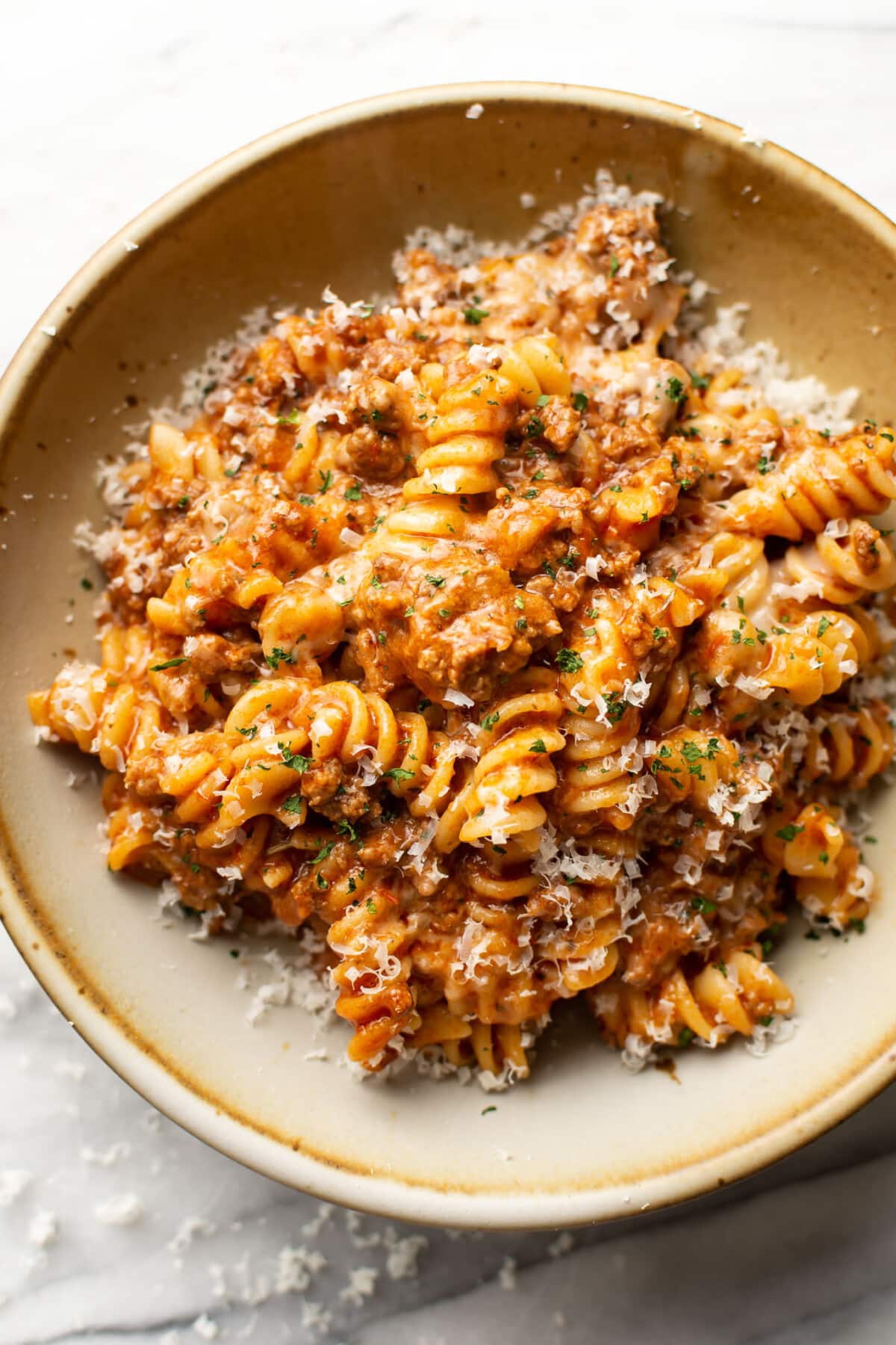 a bowl of rotini pasta with a cheesy tomato and meat sauce