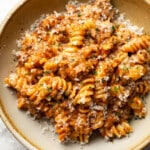 a bowl of rotini pasta with a cheesy tomato and meat sauce
