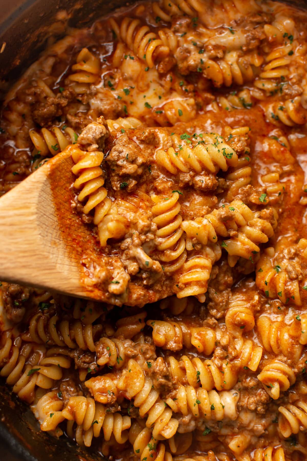 closeup of a pot of rotini pasta with a wooden spoon