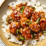 a bowl of sesame chicken with rice