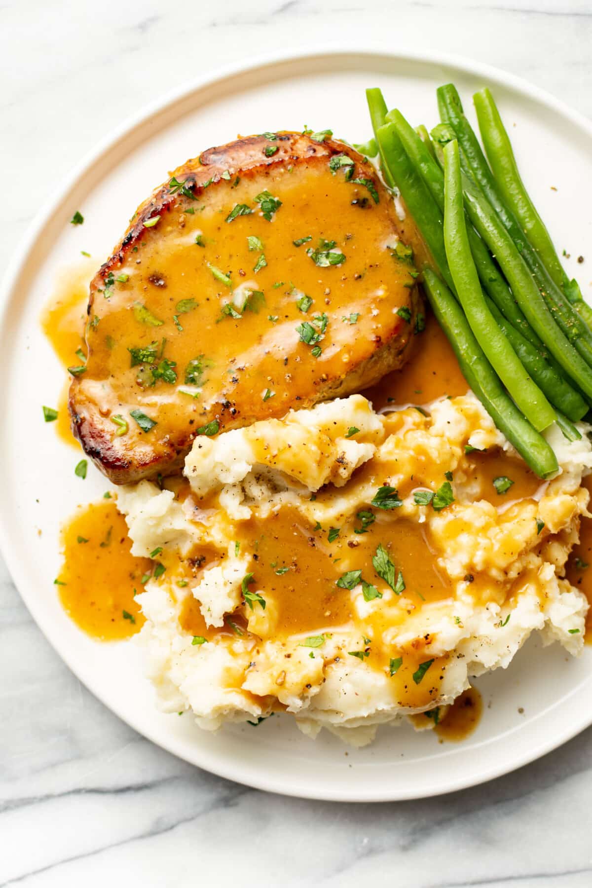 a plate with honey mustard pork chop, green beans, and mashed potatoes
