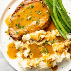 a plate with honey mustard pork chop, green beans, and mashed potatoes