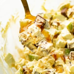 a bowl of snickers apple salad with a serving spoon