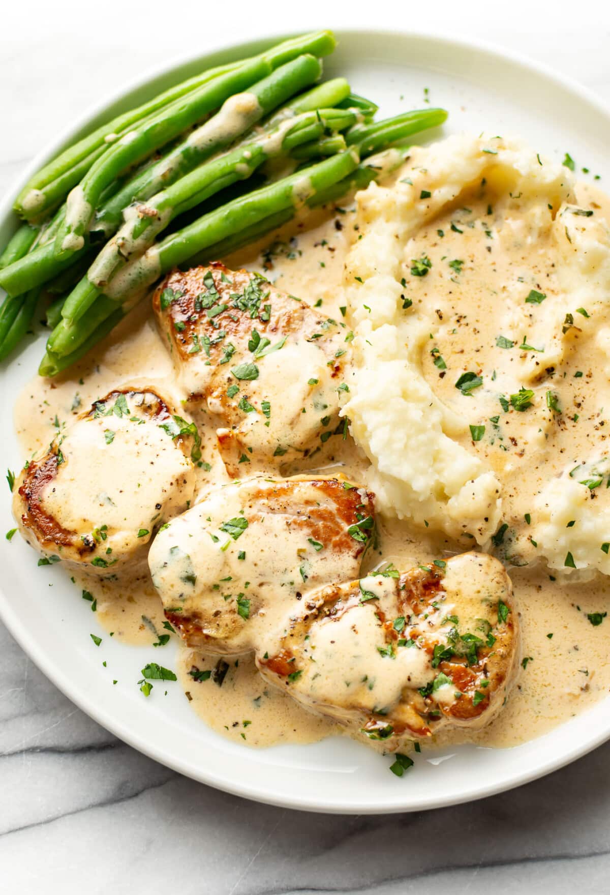 a plate with creamy white wine pork tenderloin, green beans, and mashed potatoes