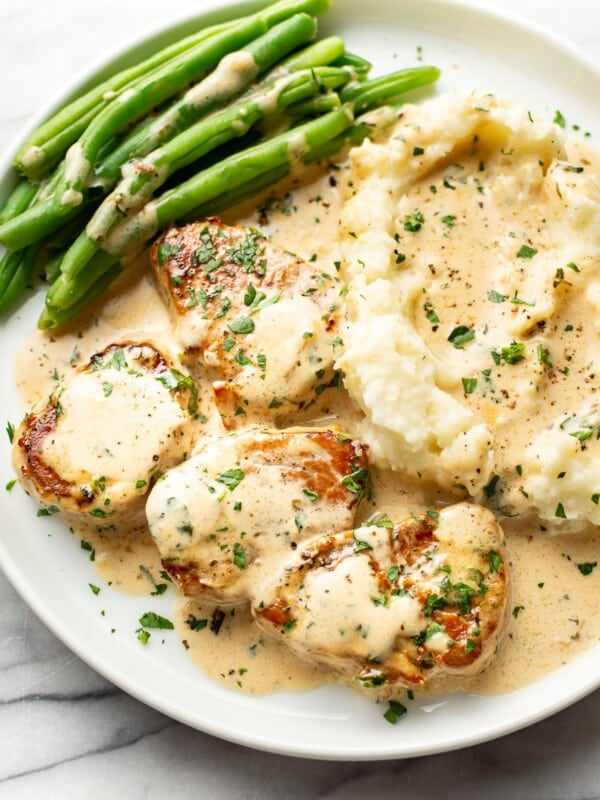 a plate with creamy white wine pork tenderloin, green beans, and mashed potatoes