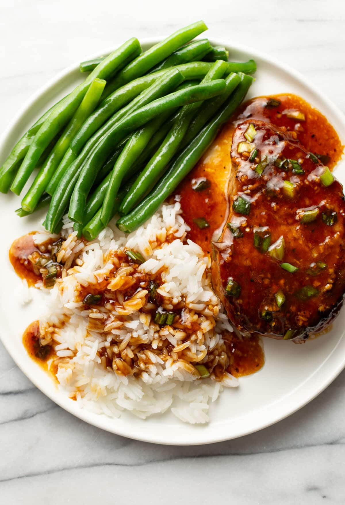 a plate with honey garlic pork chops, green beans, and rice