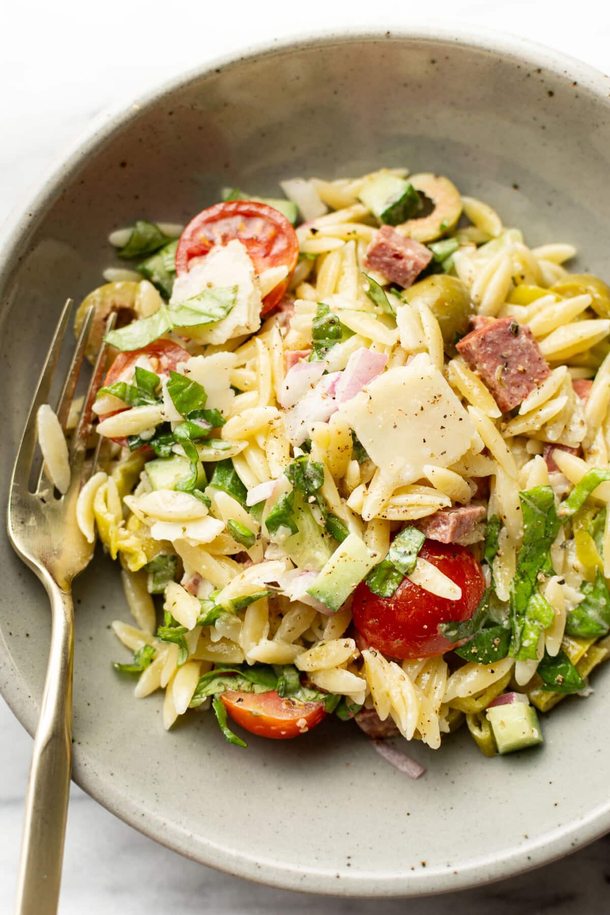 a bowl of italian orzo salad with a fork