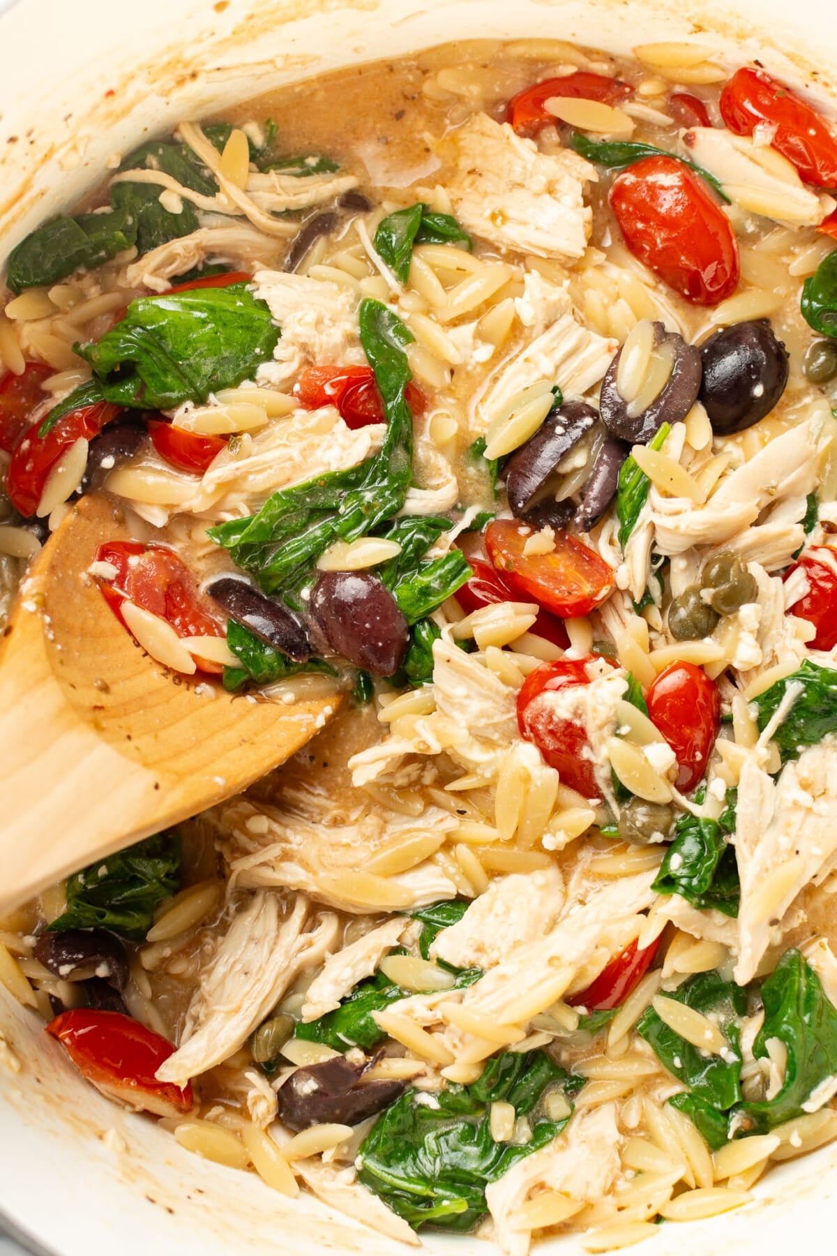 stirring a pot of mediterranean chicken orzo