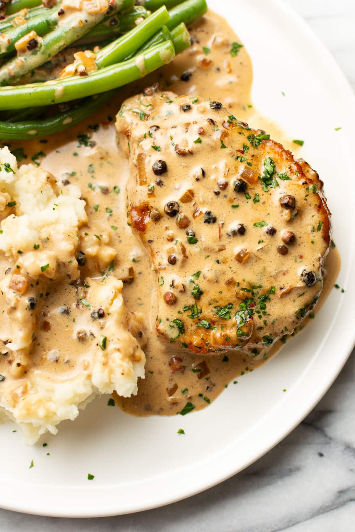 a plate with peppercorn pork chops, green beans, and mashed potatoes