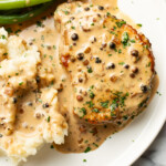 a plate with peppercorn pork chops, green beans, and mashed potatoes