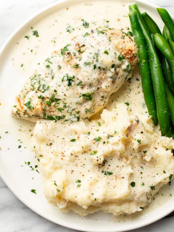 a plate with creamy baked white wine chicken, green beans, and mashed potatoes