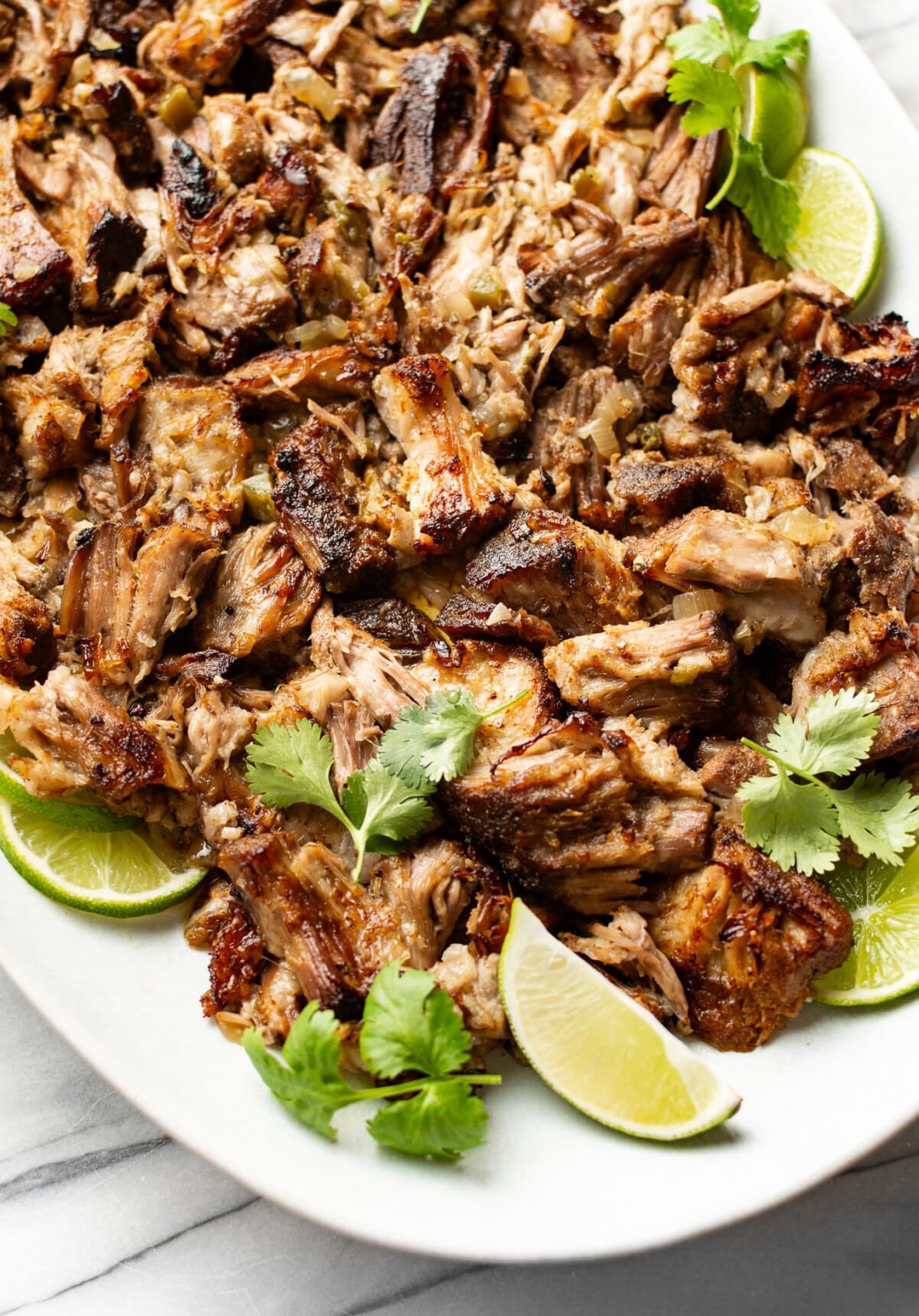 a plate with carnitas and lime wedges