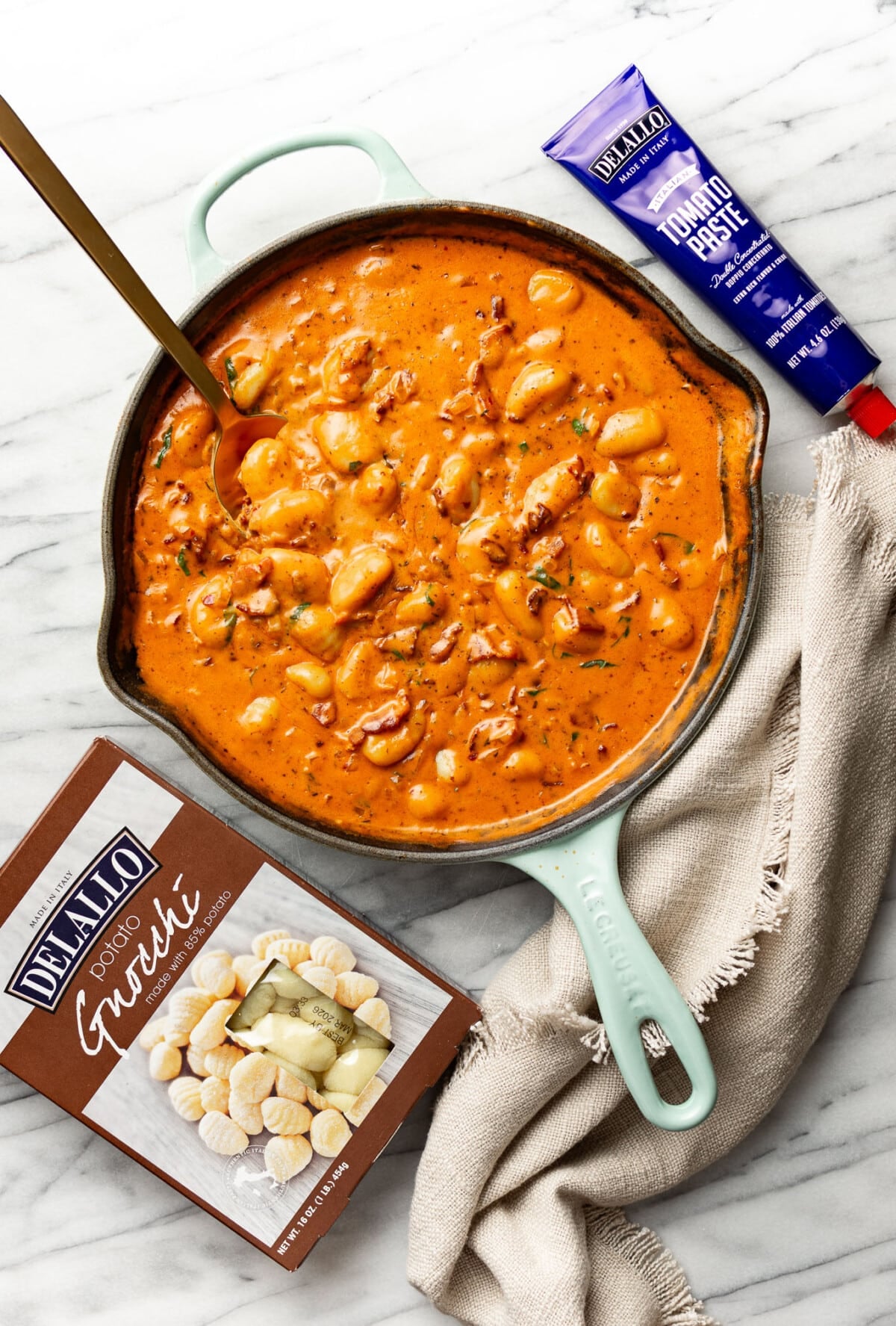 a skillet with spicy tomato gnocchi next to ingredient containers