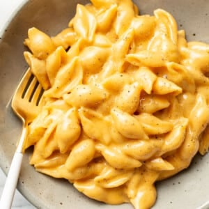 a bowl of cheesy velveeta and shells with a fork