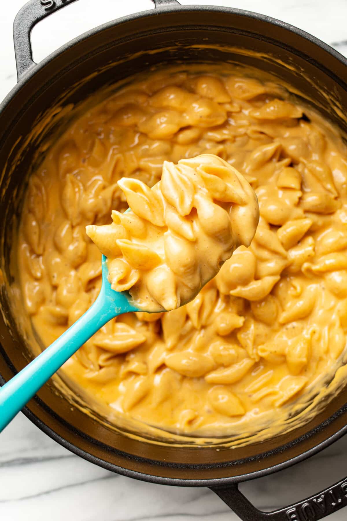 a pot of velveeta and shells with a serving spoon