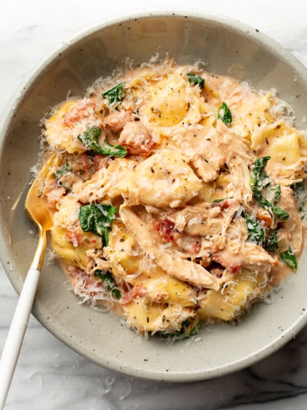 a bowl of one pan tortellini with chicken and a fork