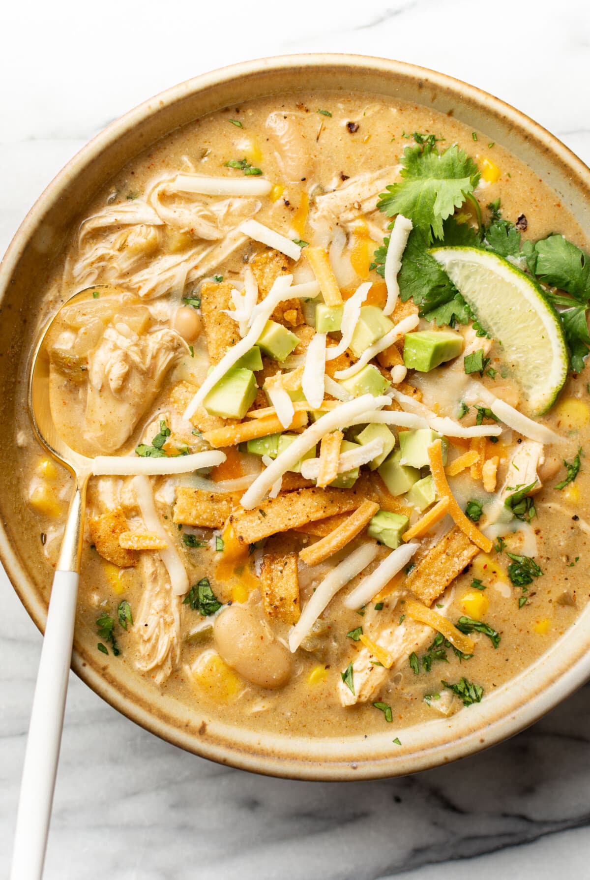 a bowl of creamy green chicken enchilada soup with a spoon