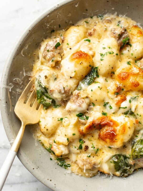 a bowl with a portion of pesto sausage gnocchi bake with a fork