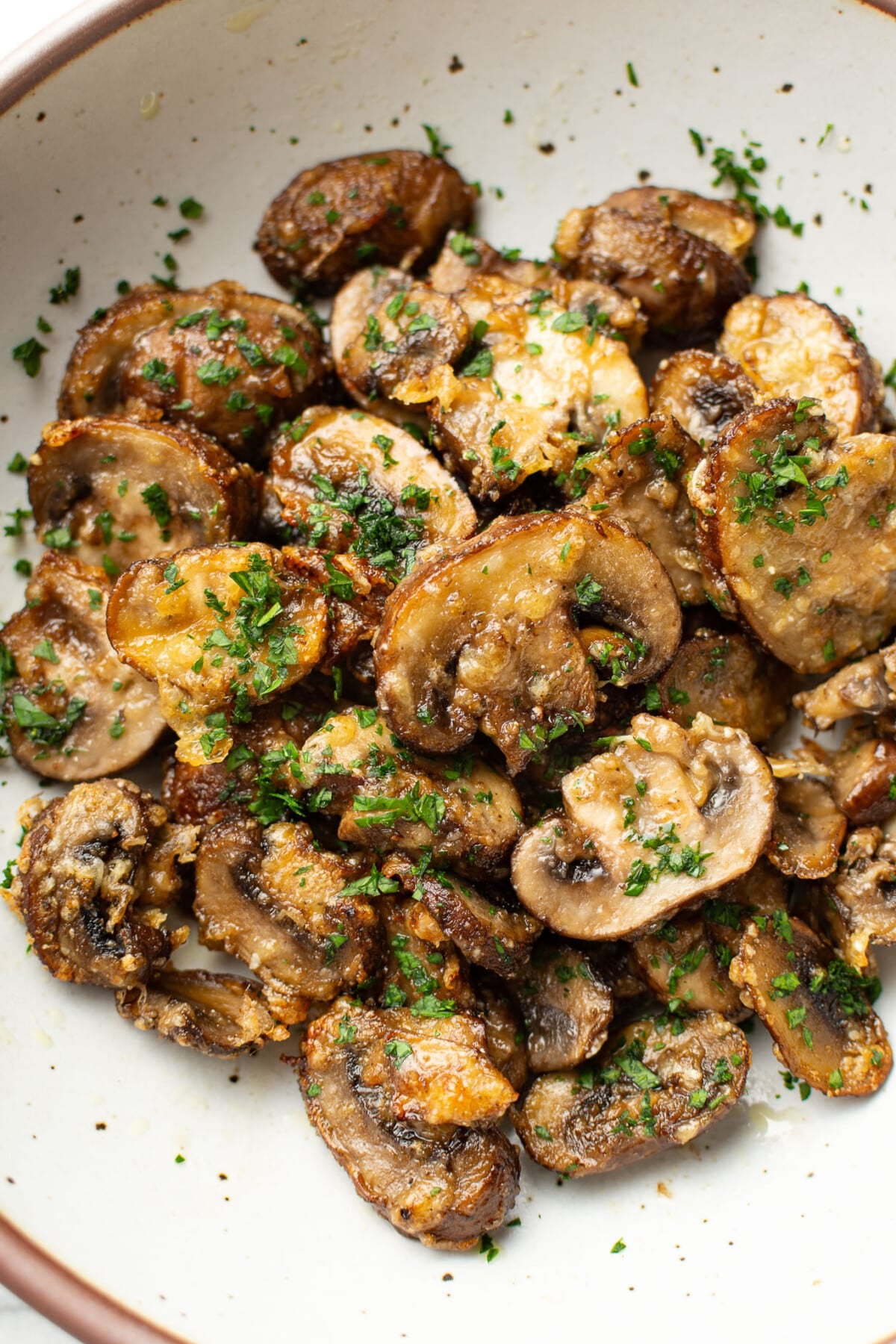 a bowl of sliced air fryer mushrooms topped with parsley
