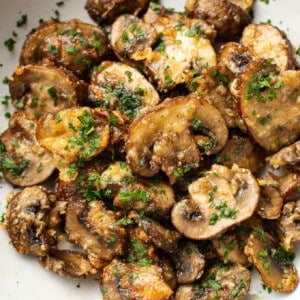 a bowl of sliced air fryer mushrooms topped with parsley